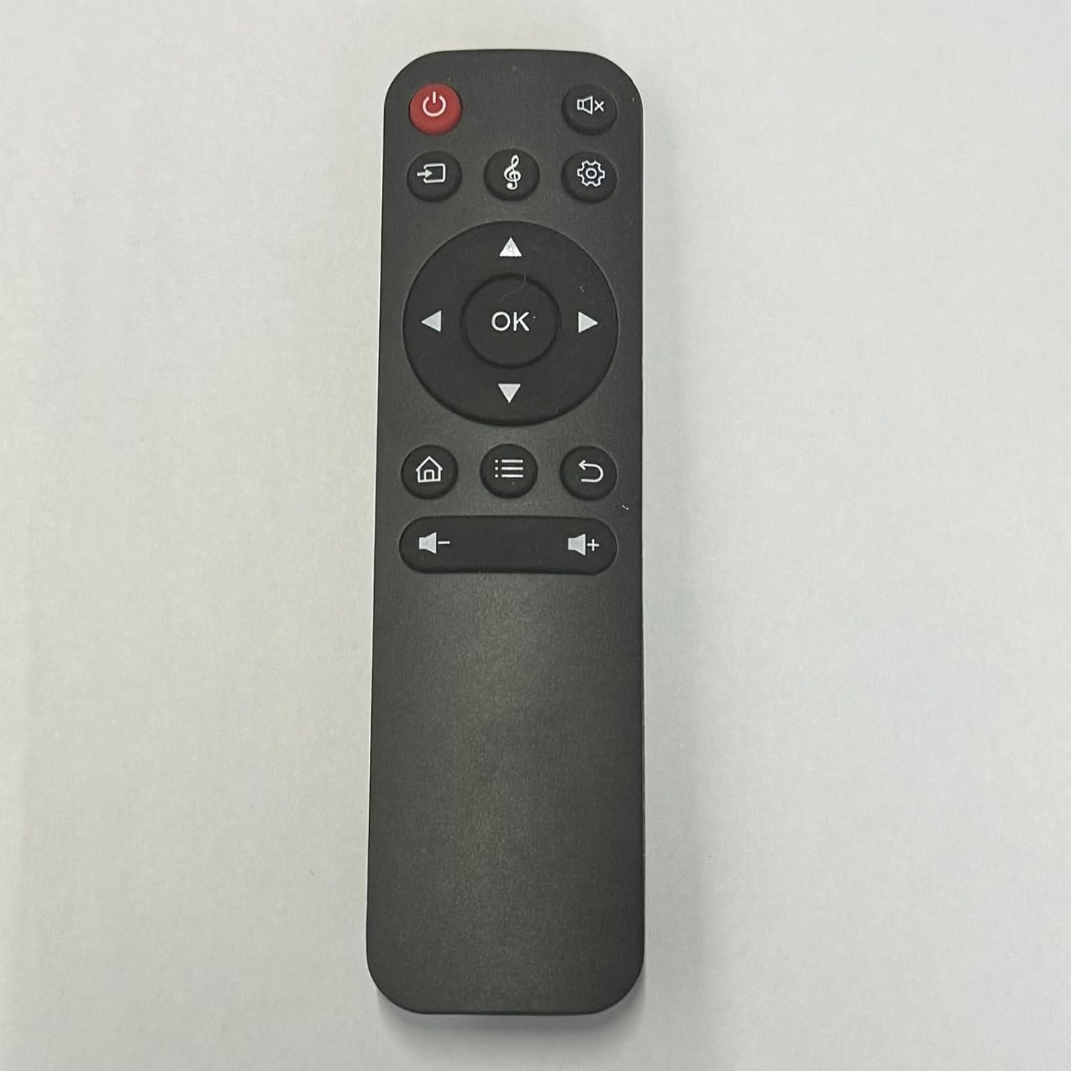 A black remote control with various buttons, including volume, power, and navigation keys, on a white background.